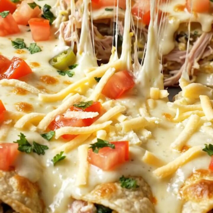 Spinach artichoke queso chicken enchilada lifted from a baking dish with strings of melted mozzarella and creamy white