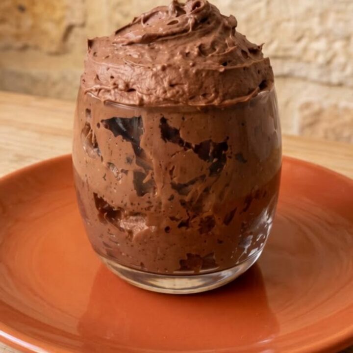 Clear glass filled with thick swirled sugar-free chocolate mousse on a terracotta plate