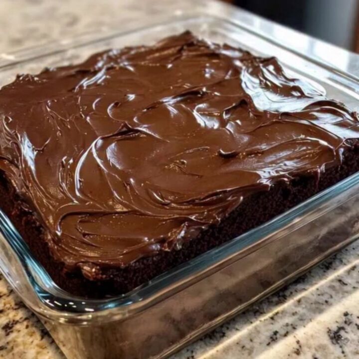 Slice of moist chocolate wacky cake with swirled chocolate frosting on a white plate