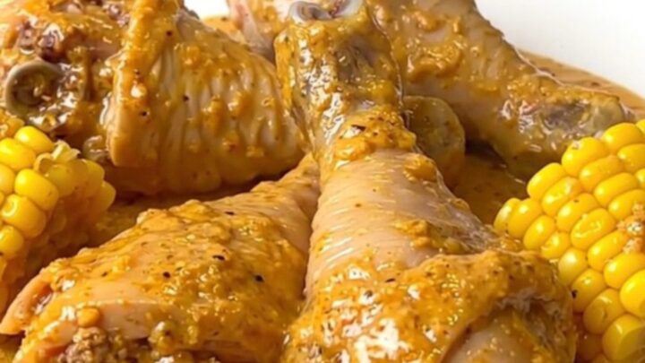 Creamy Cajun chicken drumsticks and baby corn coated in thick orange cream sauce in a black slow cooker insert