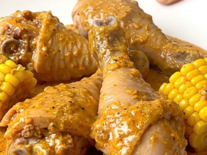 Creamy Cajun chicken drumsticks and baby corn coated in thick orange cream sauce in a black slow cooker insert