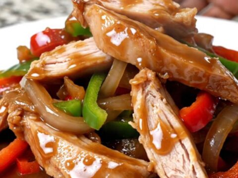 Crockpot turkey pepper steak strips with peppers and onions coated in thick brown sauce on a white plate
