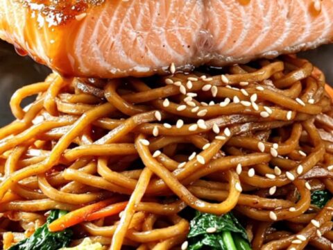 Crispy-skinned teriyaki salmon fillet glazed in glossy sauce over a steaming bowl of yakisoba noodles with charred bok choy