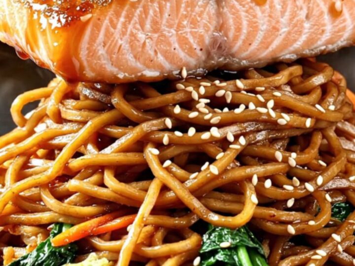 Crispy-skinned teriyaki salmon fillet glazed in glossy sauce over a steaming bowl of yakisoba noodles with charred bok choy