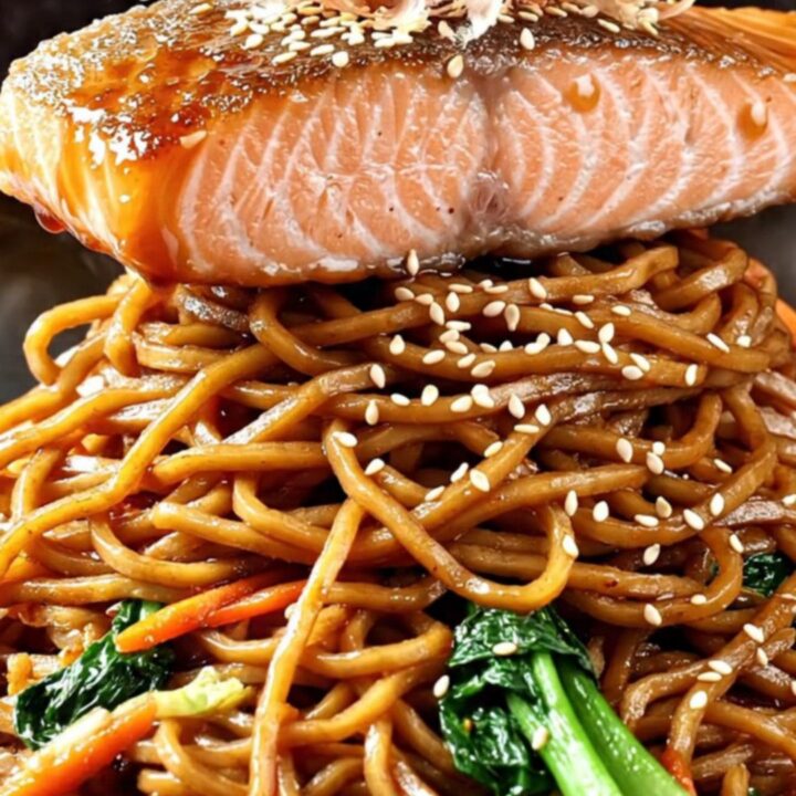 Crispy-skinned teriyaki salmon fillet glazed in glossy sauce over a steaming bowl of yakisoba noodles with charred bok choy