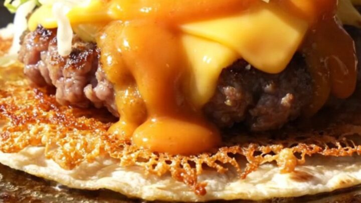 Crispy smash burger taco folded in half, lacy brown beef edge, melted American cheese and orange burger sauce drizzle