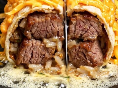 Cheese-crusted surf and turf burrito sliced in half, showing ribeye, Cajun shrimp, rice and beans inside a golden frico shell
