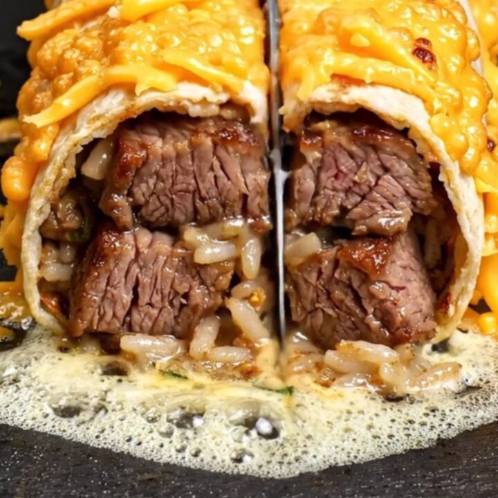 Cheese-crusted surf and turf burrito sliced in half, showing ribeye, Cajun shrimp, rice and beans inside a golden frico shell