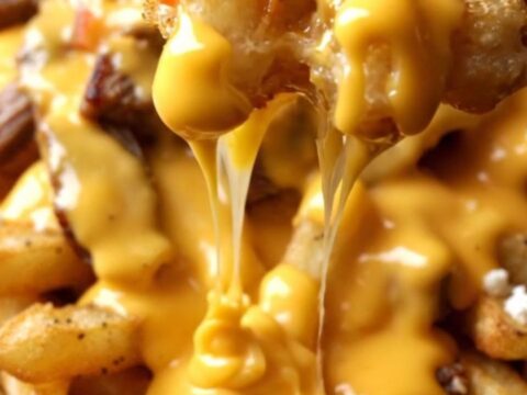 Loaded waffle fry nachos in a cast-iron skillet, molten jalapeño queso and charred steak cubes topping golden fries