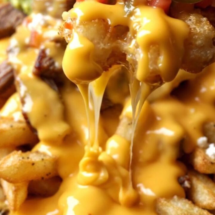 Loaded waffle fry nachos in a cast-iron skillet, molten jalapeño queso and charred steak cubes topping golden fries