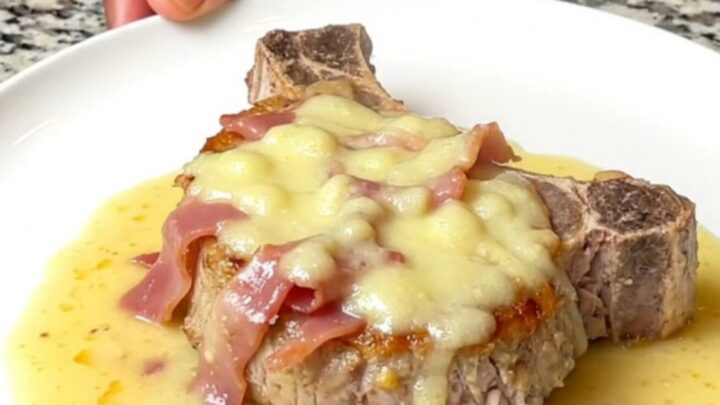 Tender slow-cooked pork chop topped with soft ham and melted Swiss cheese under a thick creamy sauce