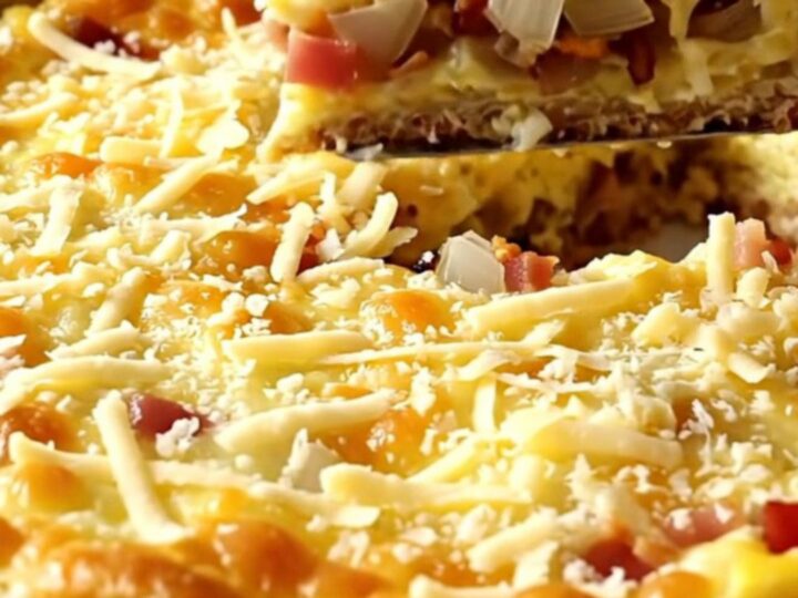 Puffed golden impossible bacon Swiss pie in a white ceramic baking dish, bubbling at the edges on a beige countertop
