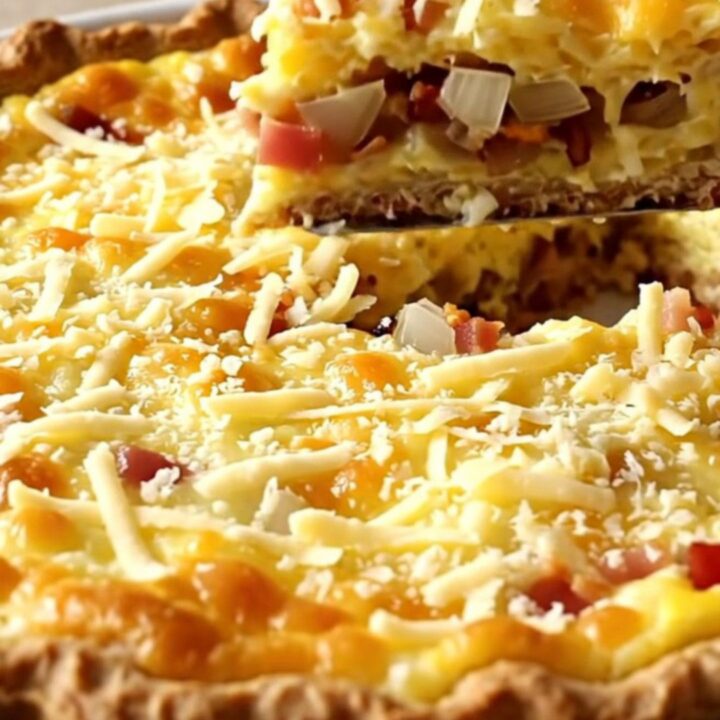 Puffed golden impossible bacon Swiss pie in a white ceramic baking dish, bubbling at the edges on a beige countertop