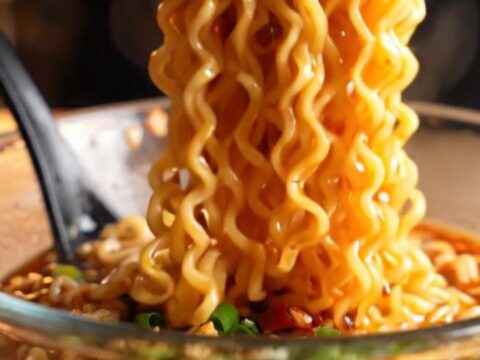 Glossy spicy garlic chili oil ramen noodles in a bowl with chopped chilies and scallions