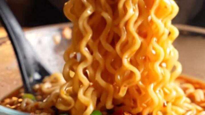 Glossy spicy garlic chili oil ramen noodles in a bowl with chopped chilies and scallions