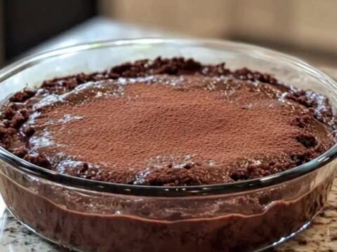 Hot chocolate pudding cake in a round clear glass dish, glossy cracked crust revealing molten fudge beneath