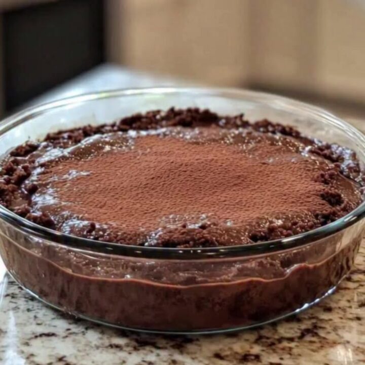 Hot chocolate pudding cake in a round clear glass dish, glossy cracked crust revealing molten fudge beneath