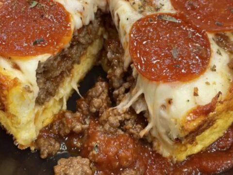 Golden impossible pizza pie with melted mozzarella and crisp pepperoni in a black pie pan
