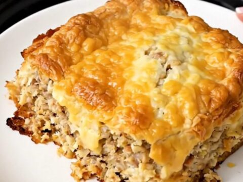 Golden crockpot sausage hash brown breakfast casserole steaming in a black oval slow cooker on a white countertop