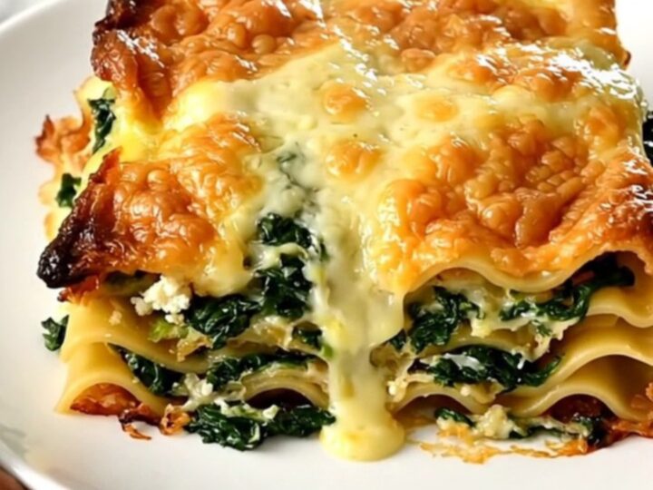 Finished slow cooker lasagna with creamy béchamel top, spinach and goat cheese layers, steaming on a white plate