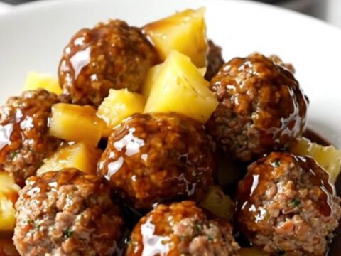 Crockpot Hawaiian turkey meatballs with pineapple and red pepper in a glossy sweet soy sauce, served on a white plate