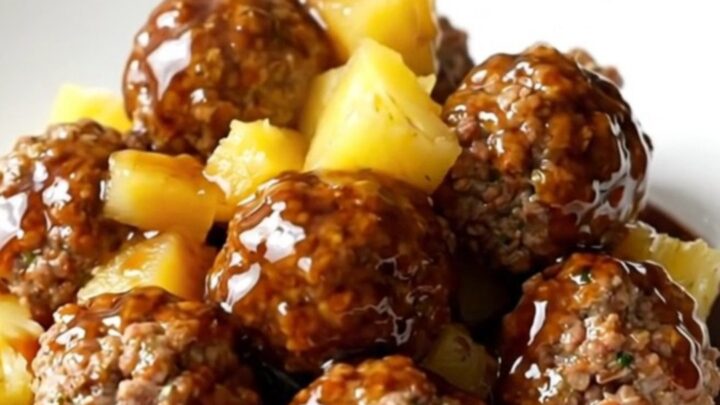 Crockpot Hawaiian turkey meatballs with pineapple and red pepper in a glossy sweet soy sauce, served on a white plate