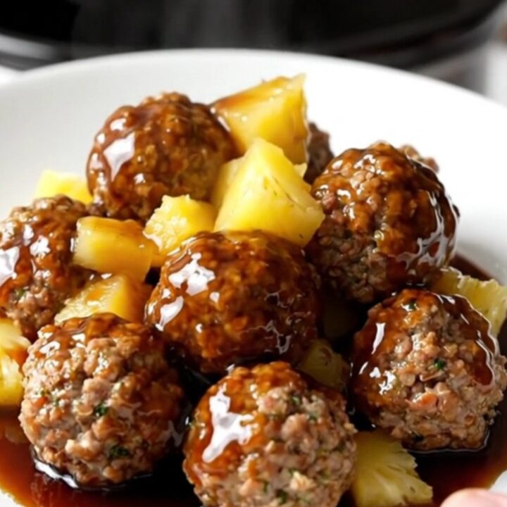 Crockpot Hawaiian turkey meatballs with pineapple and red pepper in a glossy sweet soy sauce, served on a white plate