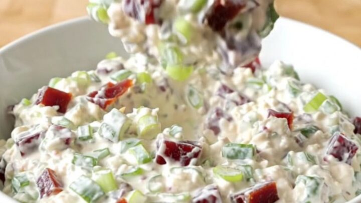 Thick creamy chipped beef dip studded with dried beef and green onions steaming in a white serving bowl