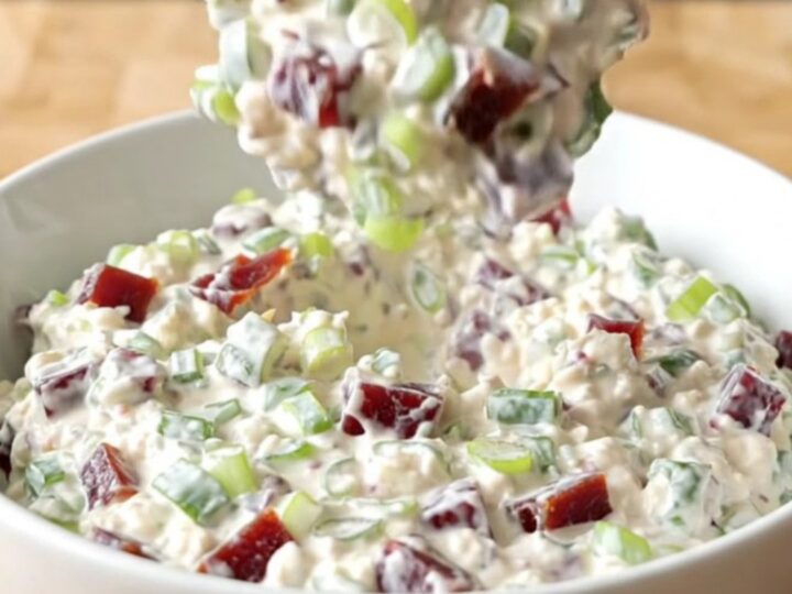 Thick creamy chipped beef dip studded with dried beef and green onions steaming in a white serving bowl