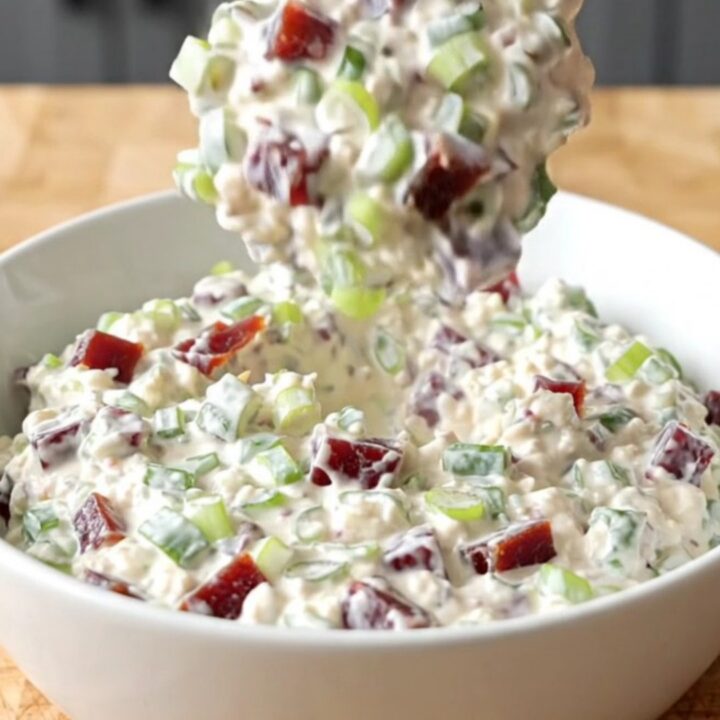 Thick creamy chipped beef dip studded with dried beef and green onions steaming in a white serving bowl