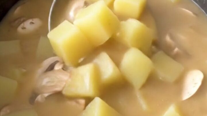 Thick creamy mushroom Swiss potato soup in a black slow cooker insert