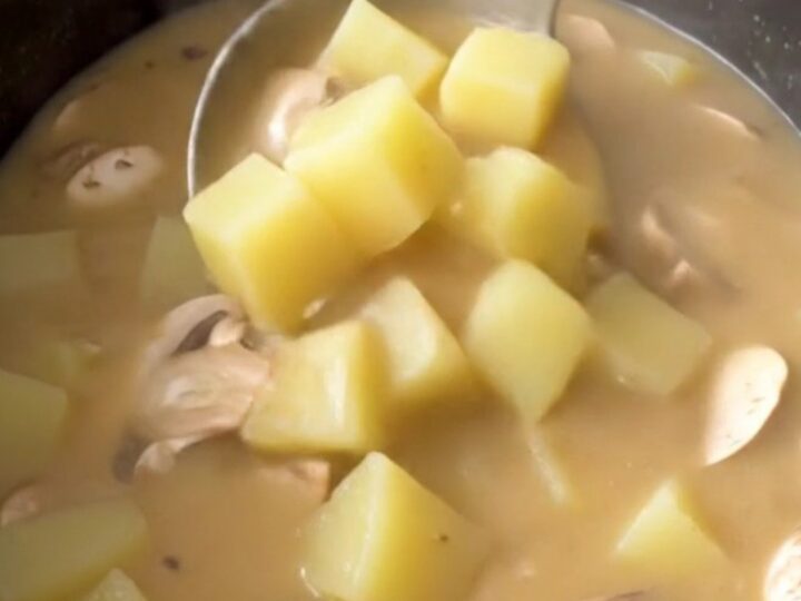 Thick creamy mushroom Swiss potato soup in a black slow cooker insert