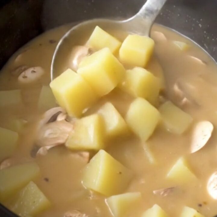 Thick creamy mushroom Swiss potato soup in a black slow cooker insert