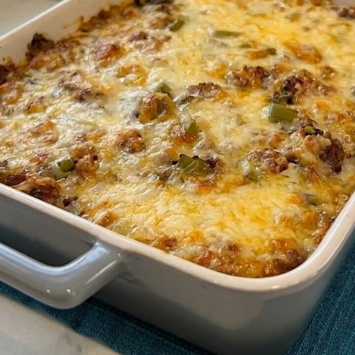 A spatula scooping a hot serving of Philly cheesesteak casserole with an extreme, stretchy cheese pull.