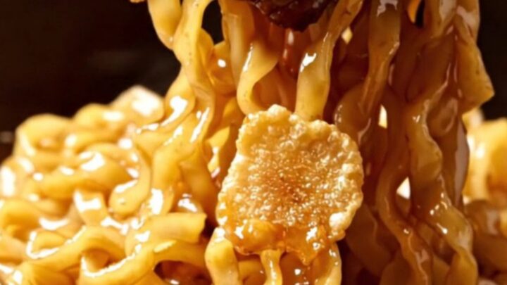 Seared Wagyu ribeye cubes with crispy garlic chips over glossy soy-butter ramen noodles in a dark bowl
