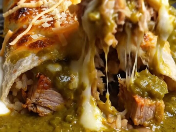 Smothered green chile carnitas burrito under bubbling Monterey Jack in a cast-iron dish
