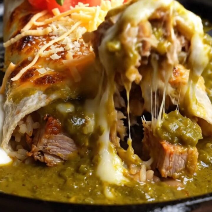 Smothered green chile carnitas burrito under bubbling Monterey Jack in a cast-iron dish