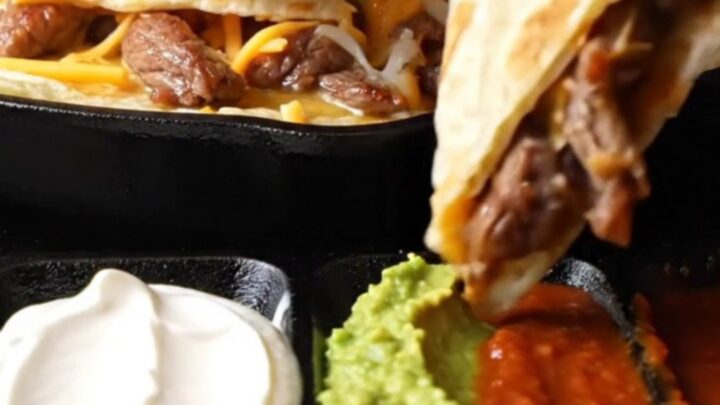 Golden steak fajita quesadilla triangle lifted with long strands of melted Oaxaca and cheddar cheese