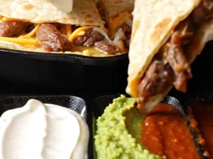 Golden steak fajita quesadilla triangle lifted with long strands of melted Oaxaca and cheddar cheese