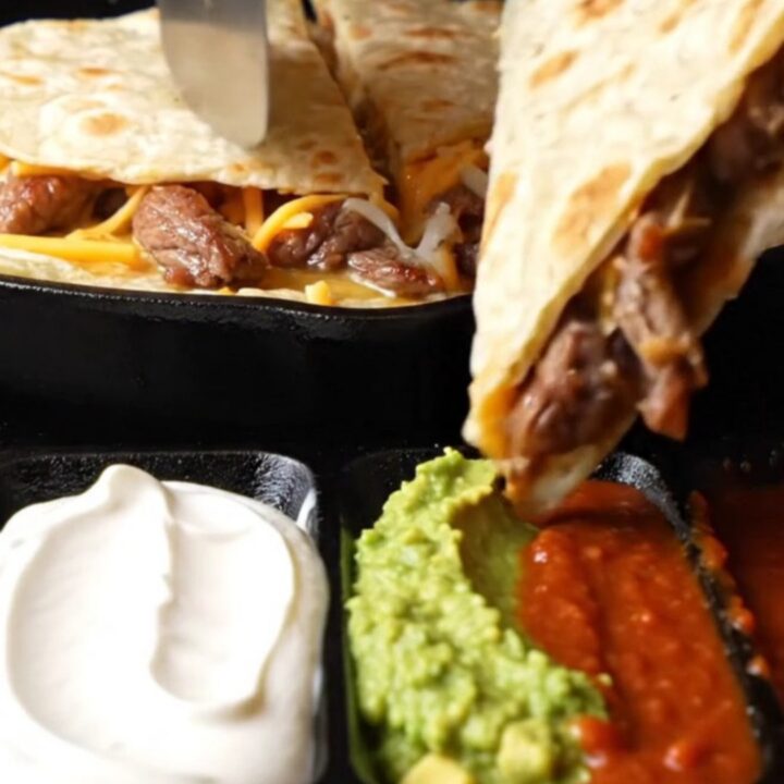 Golden steak fajita quesadilla triangle lifted with long strands of melted Oaxaca and cheddar cheese