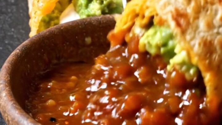 A halved burrito wrapped in a golden baked cheddar shell showing steak, guacamole and sour cream layers