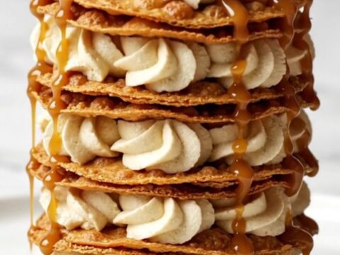 Six-layer crispy cinnamon tortilla mille-feuille topped with raspberries and caramel drizzle on a white plate