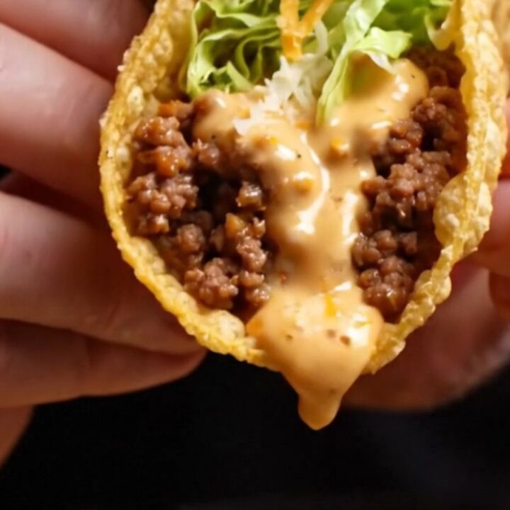 Cheesy gordita crunch copycat pulled apart showing melted cheese glue around a crispy taco shell with spiced beef