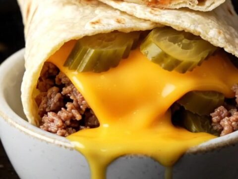 Crispy smash cheeseburger wrap sliced in half with melted cheddar and juicy beef