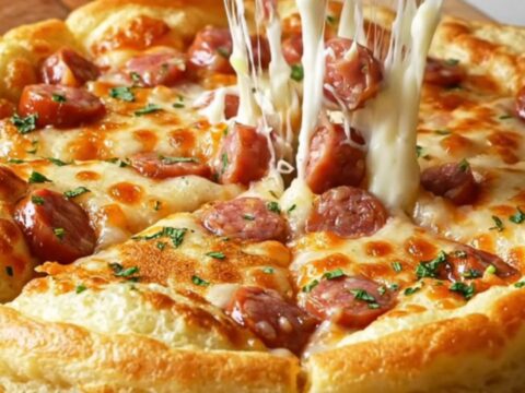 Giant savory Turkish pancake with sausage and melted cheese, sliced into wedges on a wooden board