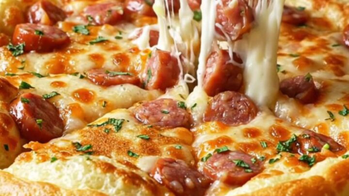 Giant savory Turkish pancake with sausage and melted cheese, sliced into wedges on a wooden board