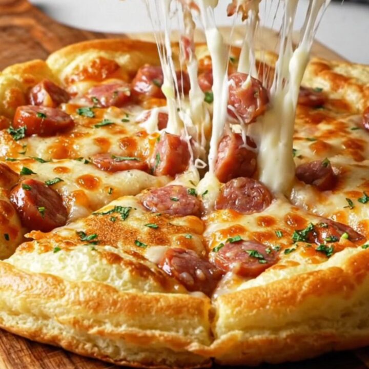 Giant savory Turkish pancake with sausage and melted cheese, sliced into wedges on a wooden board