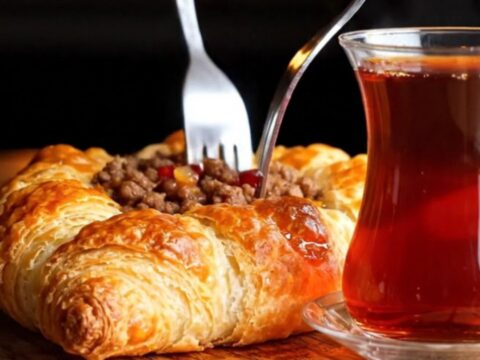 Crispy Antakya Kaytaz Börek on a baking sheet, golden blistered pastry with spiced beef filling glazed with pomegranate