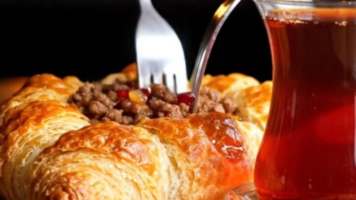 Crispy Antakya Kaytaz Börek on a baking sheet, golden blistered pastry with spiced beef filling glazed with pomegranate