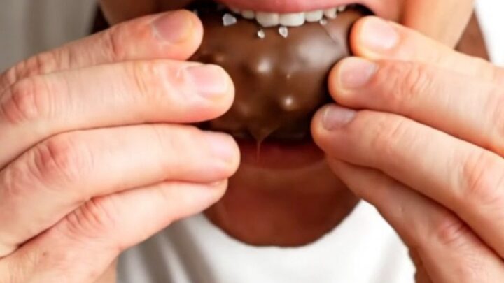 A chocolate-covered stuffed date snapped in half, showing the peanut butter and peanut filling.